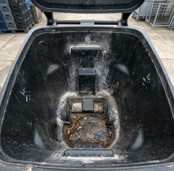 Outdoor curbside garbage bin covered in dirt and sludge before curbside service
